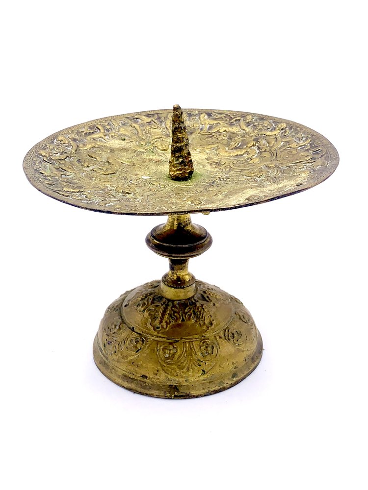 A TAKAYASATO.COM brass candle holder on a stand.
