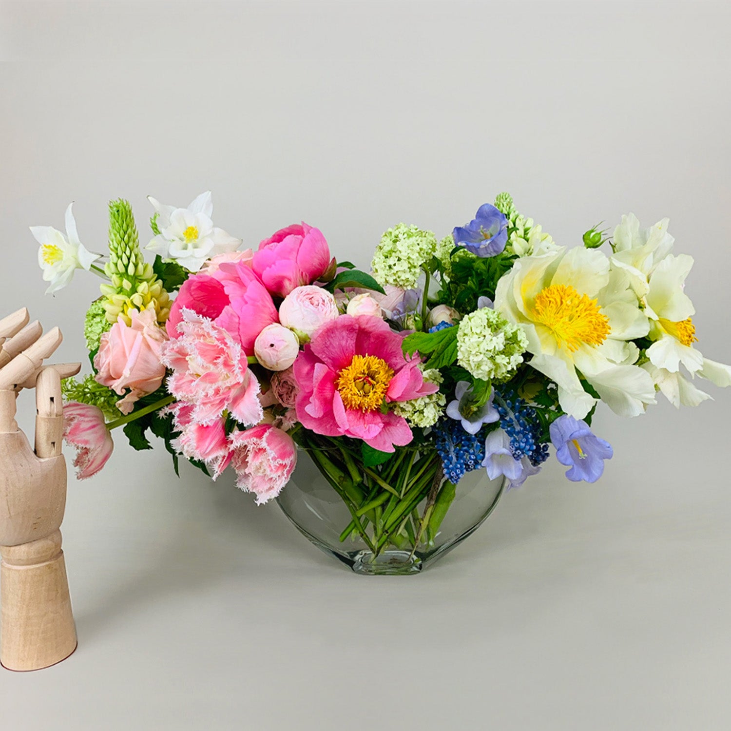 Lush colorful floral arrangement in a glass vase by Takaya Sato