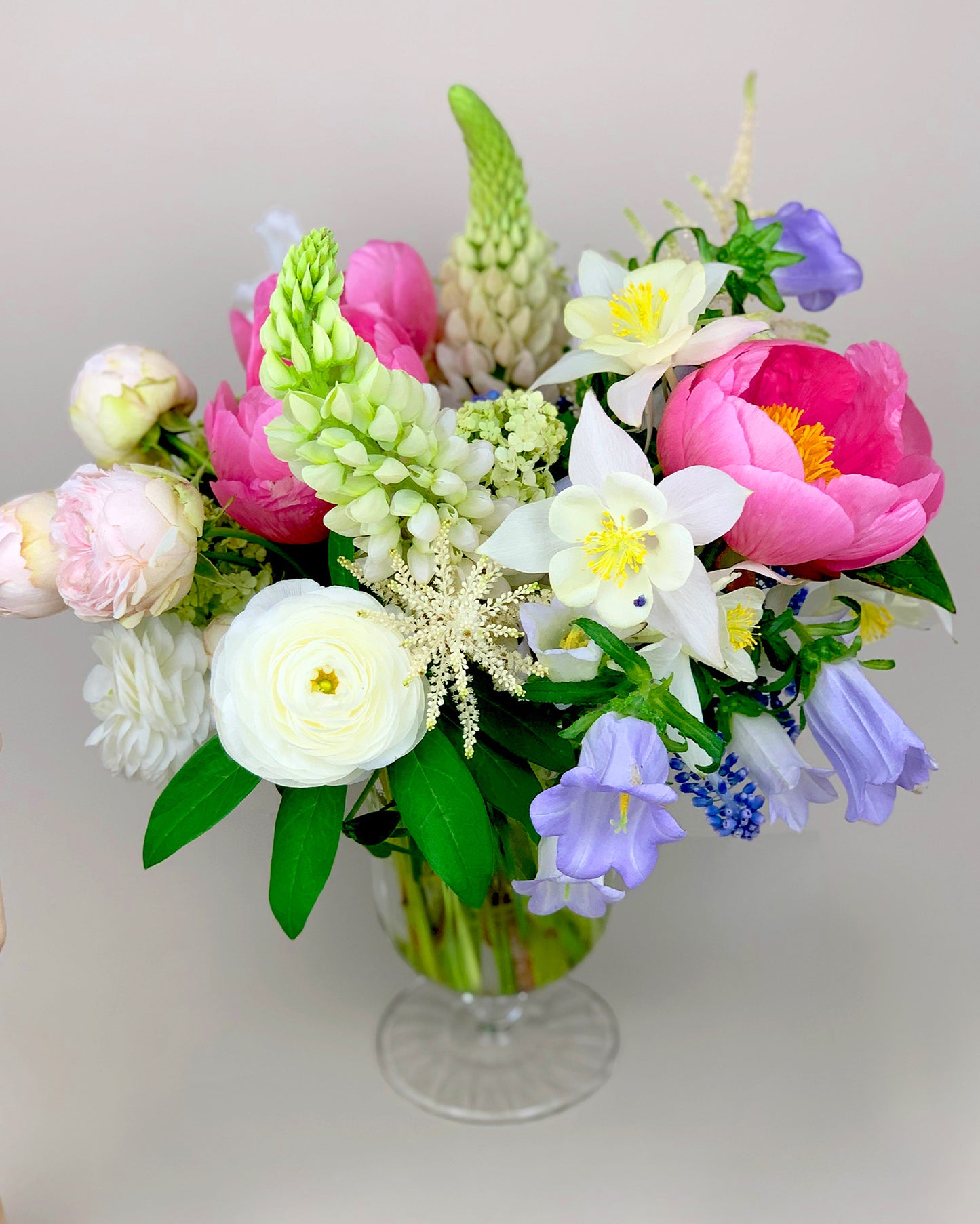 Colorful flowers in a glass vase on a table by Takaya Sato