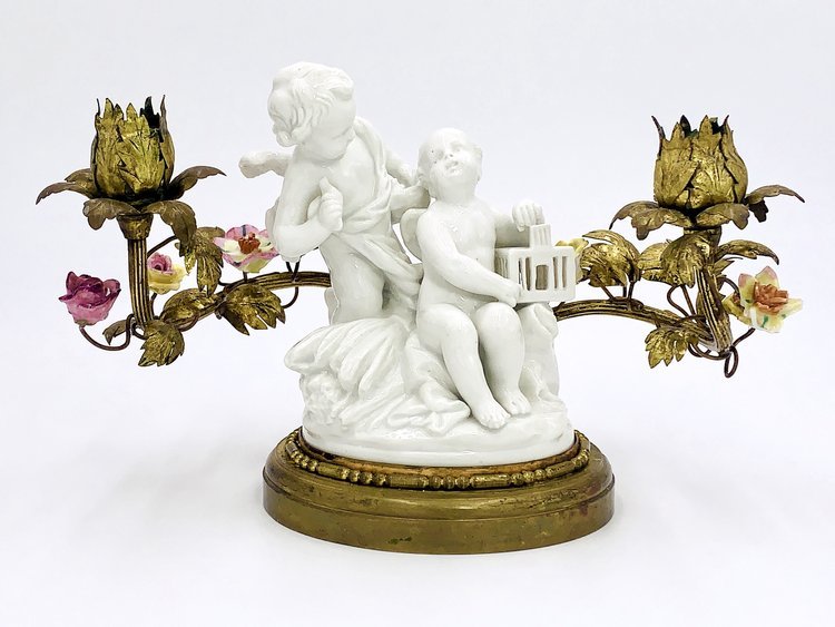 A white porcelain candle holder of Angels with the cage holding flowers, made by TAKAYASATO.COM.