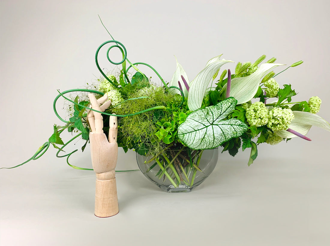 An elegant arrangement of WHITE, GREEN & HERBS flowers in a vase next to a wooden mannequin by TAKAYASATO.COM.