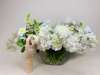 A vase filled with White,Green & Herbs flowers and a wooden mannequin creates a serene arrangement from Takayasato.com.