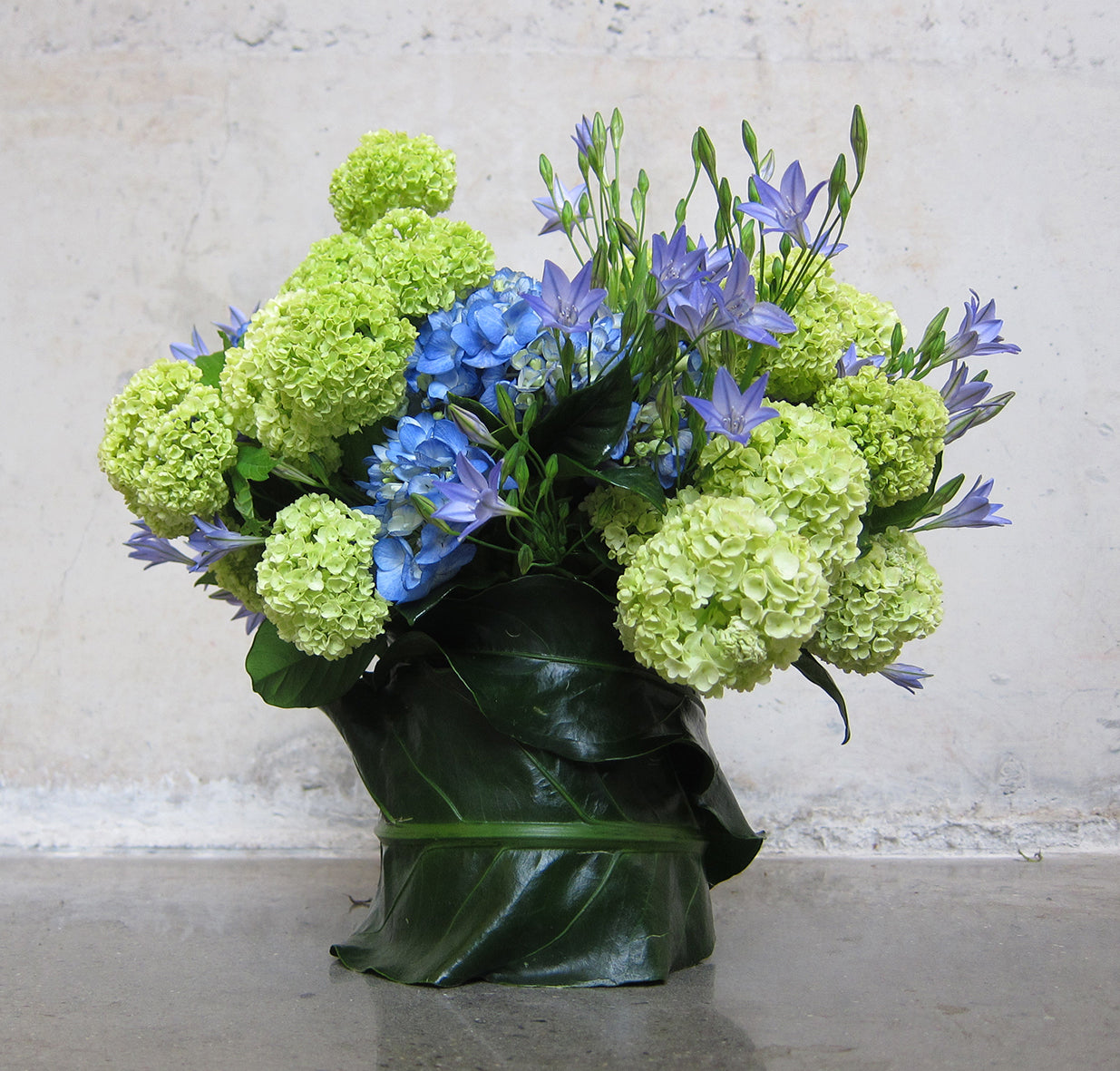 An arrangement of ECCENTRIC blue and green flowers in a vase by TAKAYASATO.COM.