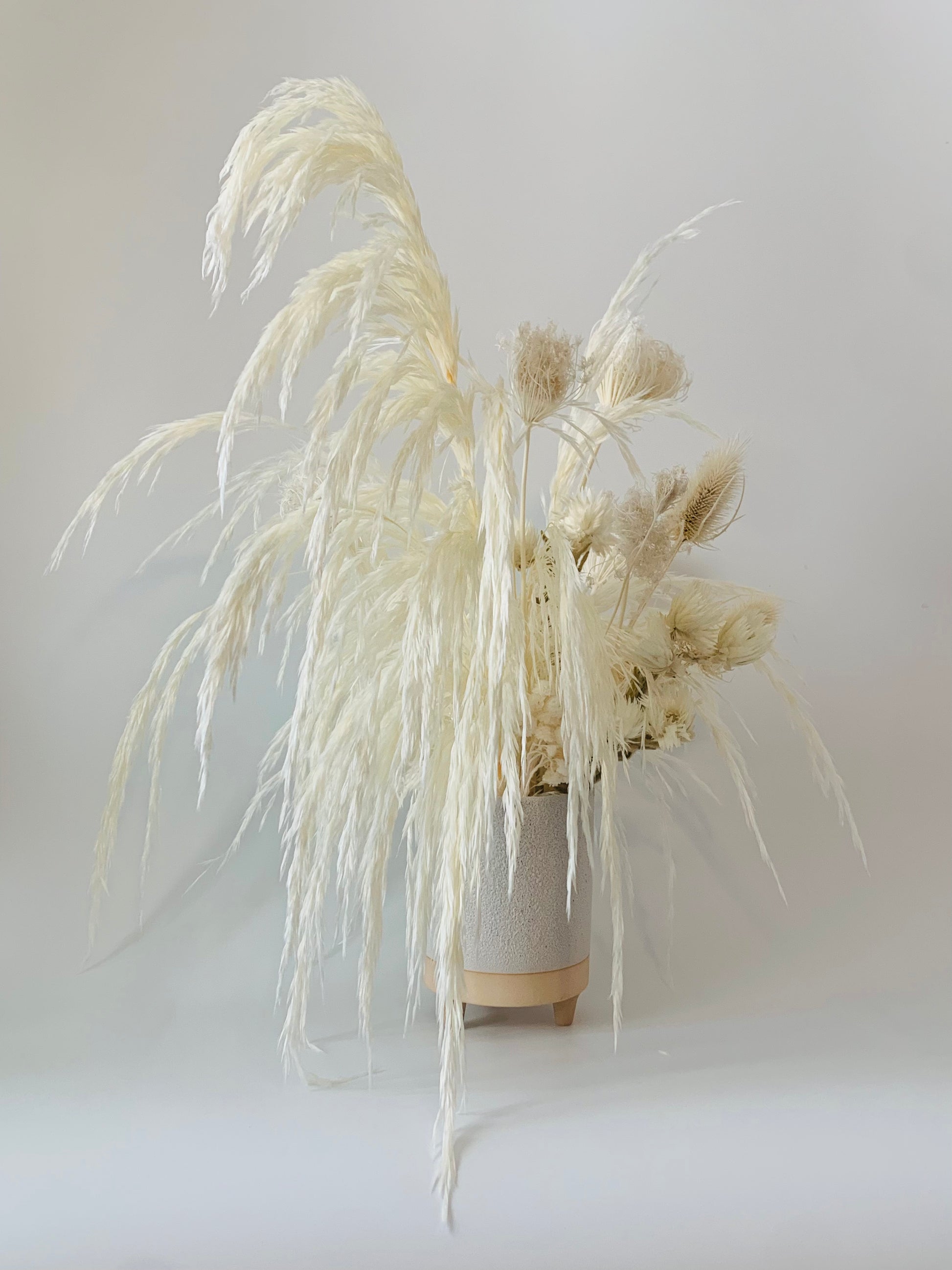 A maintenance-free, artistic white vase with dried grass in it from TAKAYASATO.COM's ETERNAL collection.