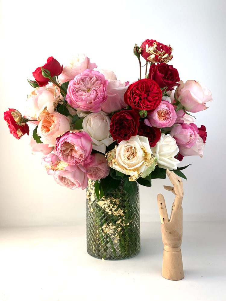 An elegant MONOFLOWER vase filled with roses and a wooden hand exudes modern sophistication from TAKAYASATO.COM.