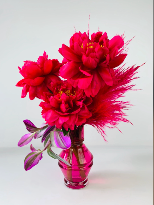 Red MONOFLOWER arrangement in a vase on a table exuding modern sophistication from TAKAYASATO.COM.