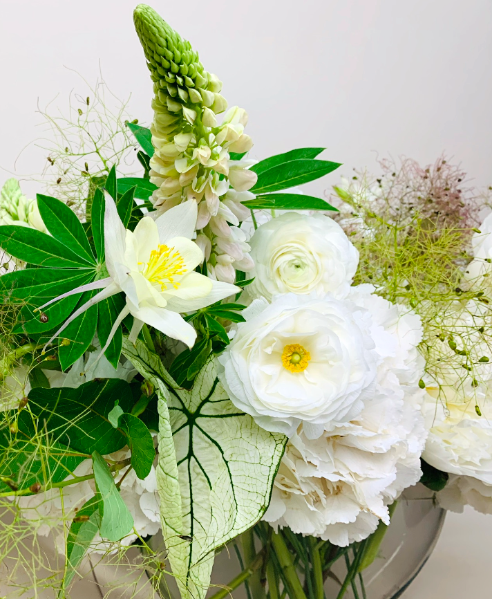 A beautiful arrangement of TAKAYASATO.COM's White, Green & Herbs flowers in a glass vase brightens up the table.