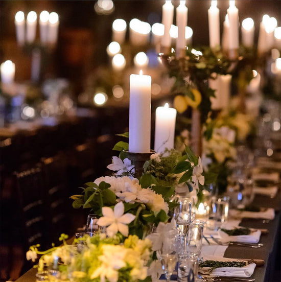 A long wedding table with candles and custom flowers as the centerpiece.