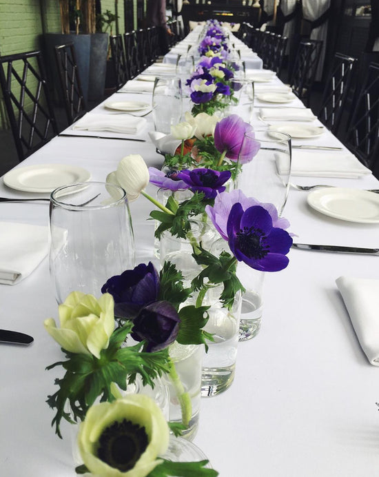 A long table with purple and white flowers as the centerpiece.