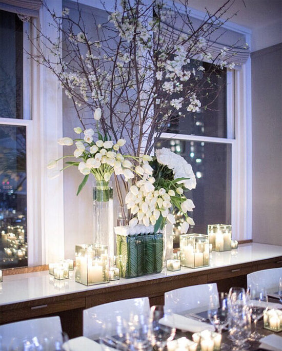 A white table setting with candles and high end flowers.