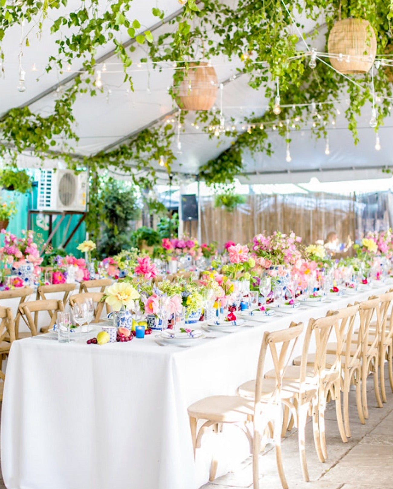 A wedding venue guest table in a tent with flowers and greenery.
