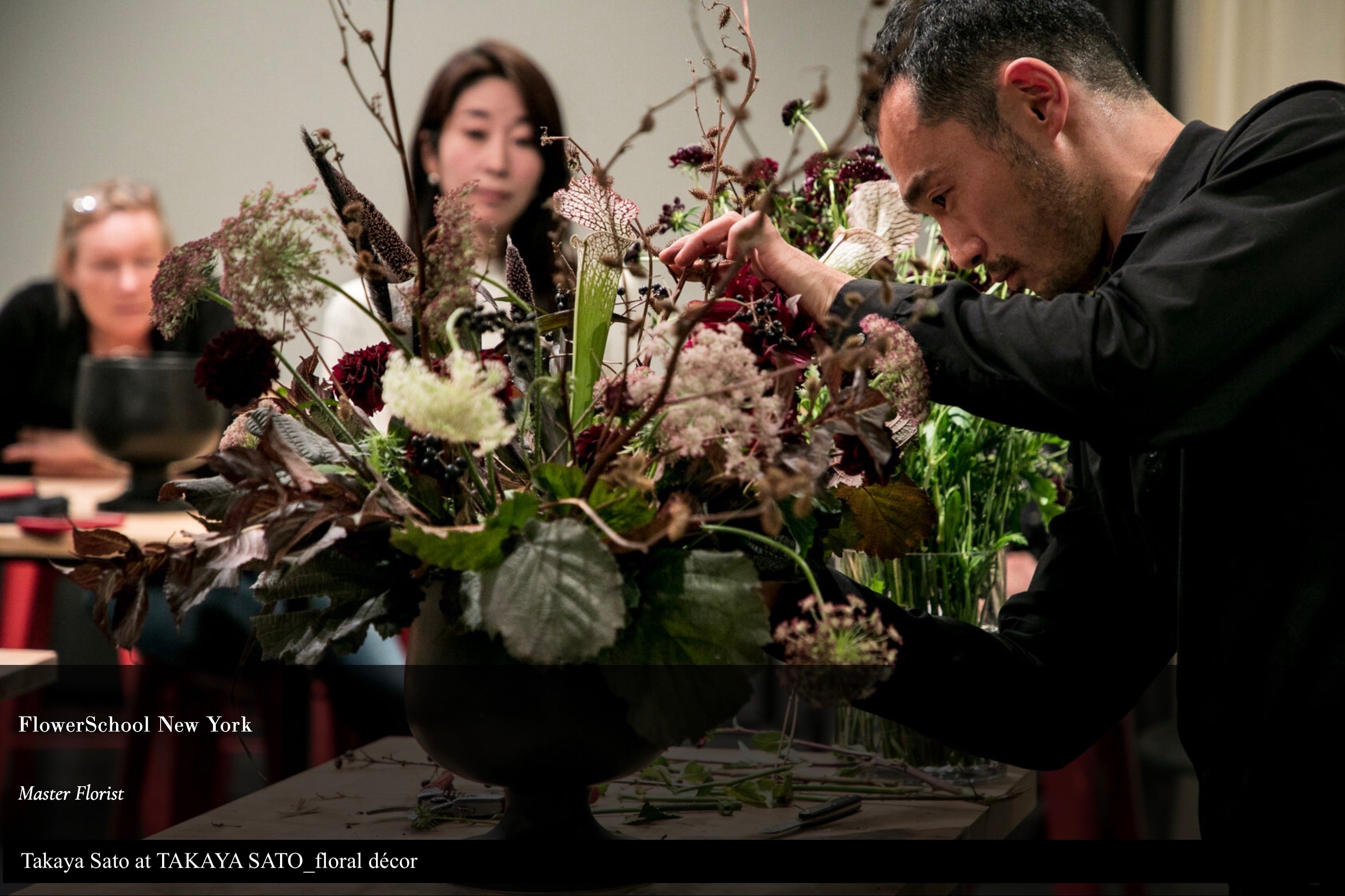 A master floral artist that is teaching customers how to arrange flowers in a vase.