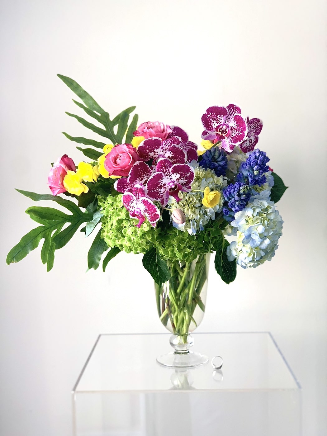Designer flower arrangements with high end orchids, hydrangeas, and green leaves.