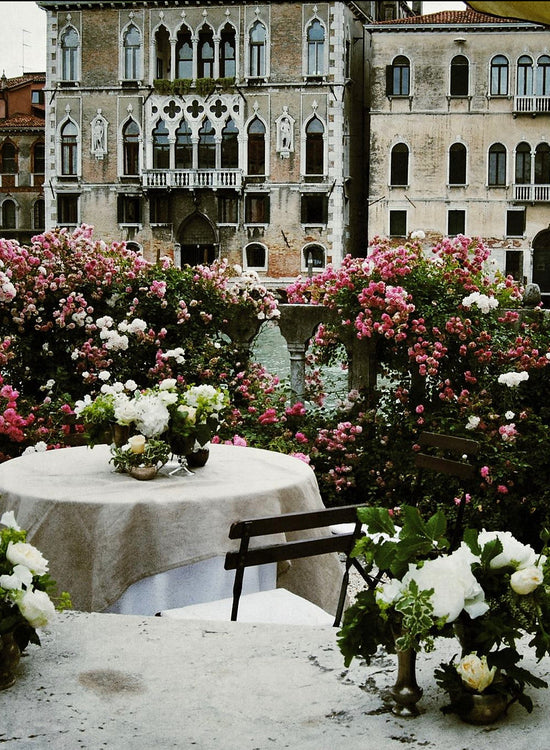 Wedding guest tables with luxurious white rose arrangements in front of an old style building.