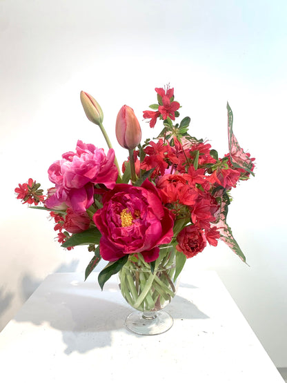 A COLORFUL vase filled with red flowers sits on the table by TAKAYASATO.COM.