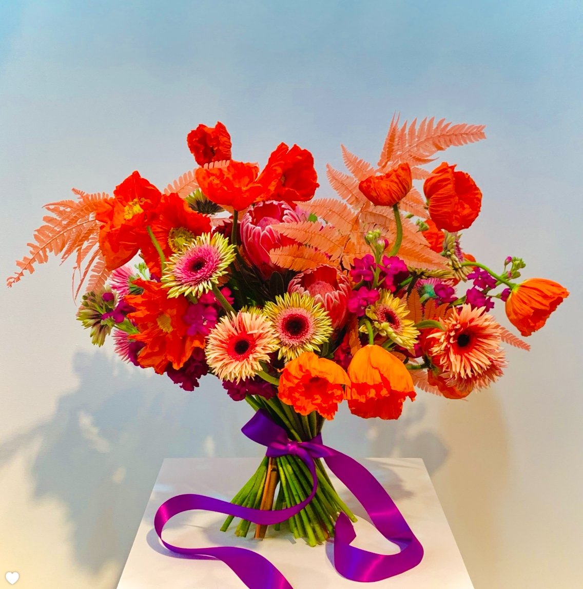 An arrangement of colorful flowers with a purple ribbon from TAKAYASATO.COM.