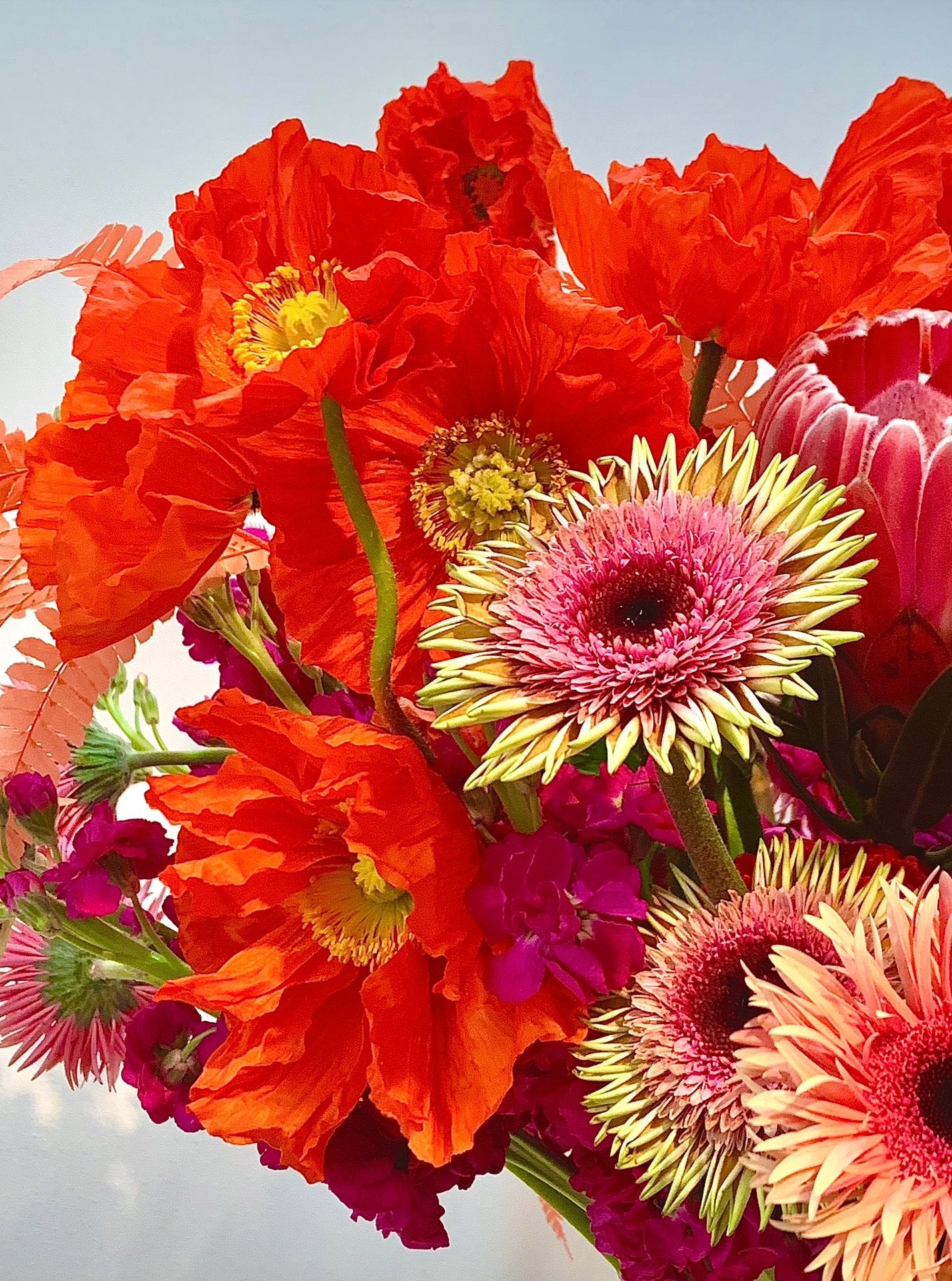 An arrangement of COLORFUL flowers in a vase by TAKAYASATO.COM.