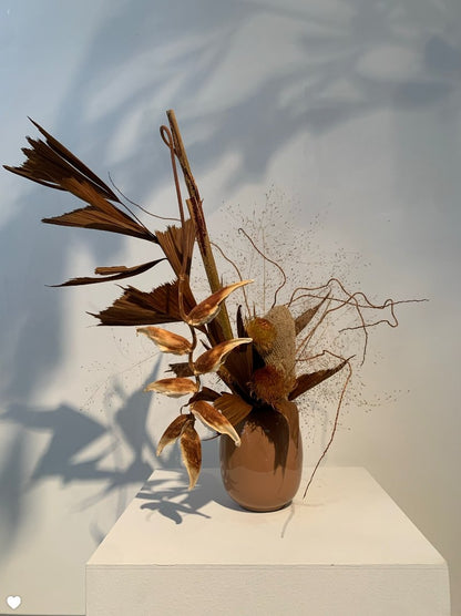 An Takayasato.com Eternal vase adorned with brown leaves, showcasing an artistic flair.
