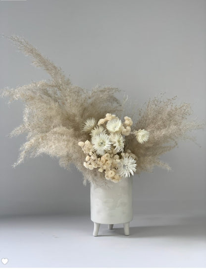 An Eternal Arrangement of dried grasses in a white vase by TAKAYASATO.COM.