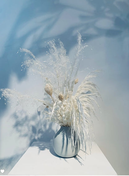 An ETERNAL Arrangement of white flowers in a vase on a table from TAKAYASATO.COM.